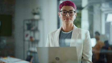 Modern Office: Portrait of Beautiful Authentic Specialist with Short Pink Hair Standing, Holding Laptop Computer, Looking at Camera, Smiling Charmingly. Working on Design, Data Analysis,Plan Strategy  - Powered by Adobe