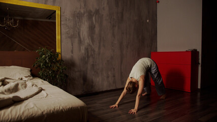 Lifestyle yoga at home. A beautiful girl at dawn does yoga asanas to recharge her energy for a busy day.