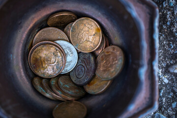 Bulgarian coins in a metal bowl on an asphalt road.