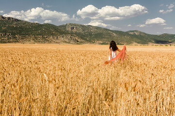 A woman in a scarf walking through a barley field in Antalya