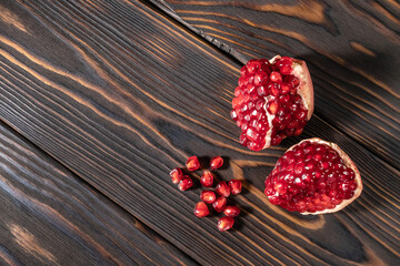 Craked ripe pomegranate on dark wooden background
