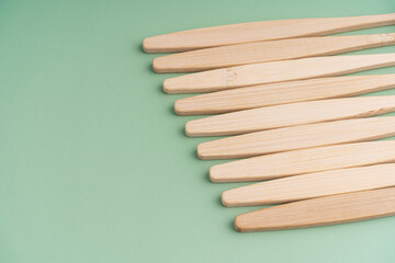 A set of Eco-friendly antibacterial toothbrushes made of bamboo wood on a light green background. Environmental care trends