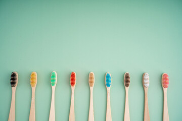 A set of Eco-friendly antibacterial toothbrushes made of bamboo wood on a light green background....
