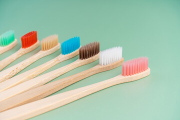 A set of Eco-friendly antibacterial toothbrushes made of bamboo wood on a light green background. Environmental care trends