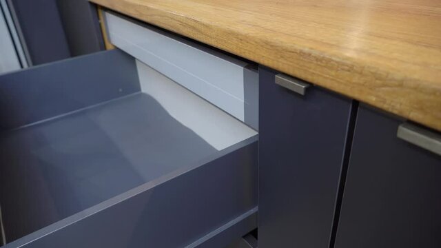 Modern stylish grey and black kitchen Cabinet with a door or drawer that opens with a woman's hand, close-up. Modern stylish kitchen