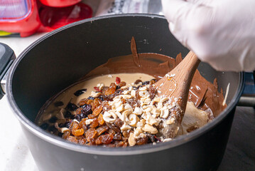 Close up on energy bars ingredients mixed in a black pot, stirring with a wooden spoon