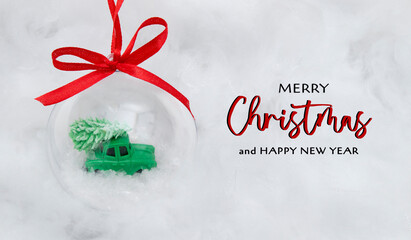 Congratulation of merry christmas on snow background with transparent christmas ball with a toy car...