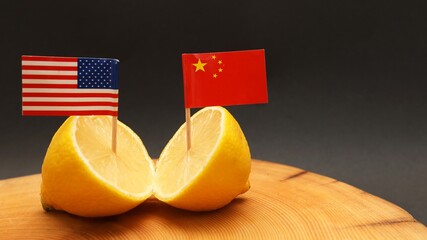 US American and Chinese flags in a sliced lemon on a chopping block representing the strained...