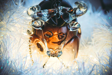 Dark brown glass bull close-up on the background of Christmas tinsel and flashlights