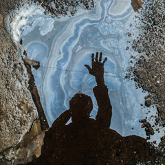Silhouette of man reflected in dirty puddle