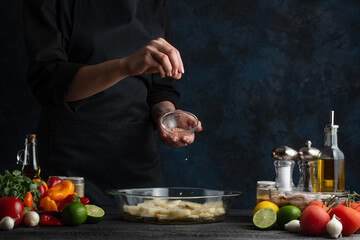 The professional chef squeezes lime juice on raw potatoes. Backstage of cooking traditional asian...