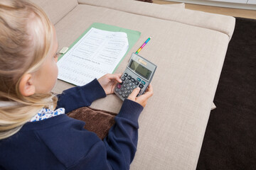 Girl using calculator while studying on sofa