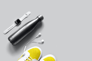 sports essentials flat lay with reusable water bottle, smart watch and sneakers toned