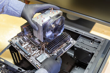 Upgrade or PC assembly concept. Technician installs a new motherboard with a large CPU cooler in a...