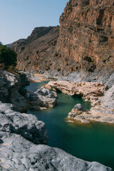 Fototapeta na wymiar a river with a rocky cliff and a blue sky
