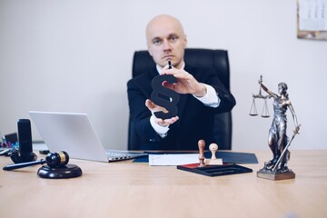 Attorney in the office holds a paragraph in his hand as a sign of justice and law.