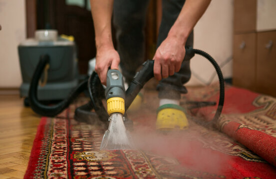 The Process Of Cleaning Carpets With A Steam Vacuum Cleaner. An Employee Of A Cleaning Company Cleans The Carpet Using Steam.