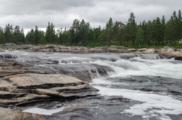 Rocky whitewater river with rapids and forest