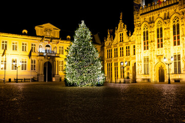 Fototapeta na wymiar Christmas tree on Burg square and City Hall in Bruges, Belgium. Festive lights and decorations.
