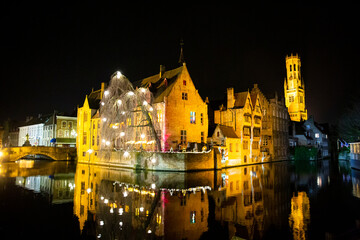 Fototapeta premium Historical city center in Bruge at night, Belgium. Old medieval buildings reflect in the water. Christmas.
