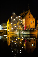 Naklejka premium Historical city center in Bruge at night, Belgium. Old medieval buildings reflect in the water. Christmas.