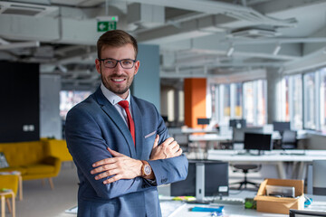 Portrait of a handsome businessman with eyeglasses standing in the office.