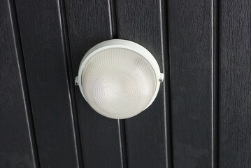 one white round glass shade on the chandelier hangs on the black ceiling in the room
