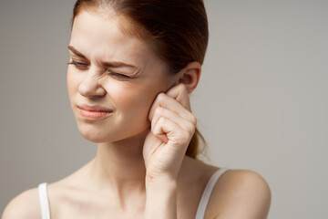 woman in white t-shirt holding ears discontent migraine health problems