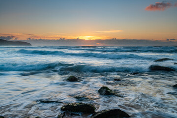 Sunrise seascape with light cloud, waves and rocks