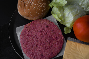 Raw meat for burger on comal with cheese lettuce tomato and bun ready to gril