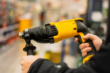 Man holds a yellow puncher for repair work in his hands against the backdrop of showcases in a...