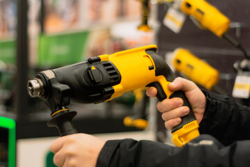 Man holds a yellow puncher for repair work in his hands against the backdrop of showcases in a...