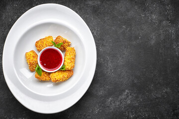 Nuggets with raspberry jam and mint leaves, on a white plate, on a dark background