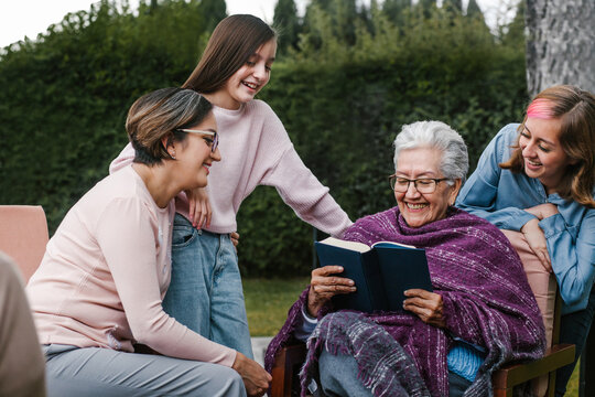 Latina Women Family Reading A Book In A Backyard Outside Home In Mexico City