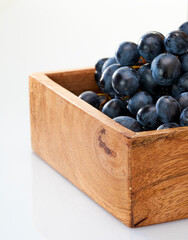 Dark red grapes lie in a box made of mango wood on a white background.Isolate.