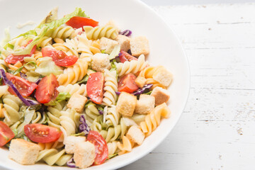 Pasata salad with fresh vegetables on a wooden table