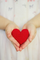 child's hands holding knitted heart