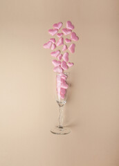 .Wine glass with pink hearts on a beige background. Flat composition, top view. Valentine's Day. Romantic. Wedding.