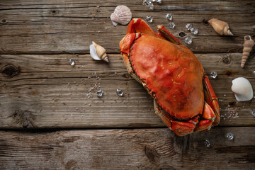 Appetizing cooked crab with seashells on rustic wooden background. Delicious meal. Seafood concept. View from above. Space for text. Flat lay.