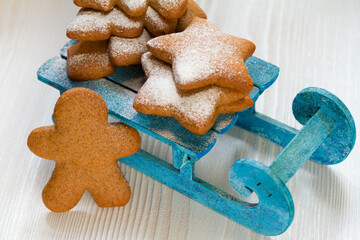 Gingerbread cookie in the form of a man, trees and stars on a blue sled, background