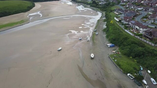 Boats On River Gannel During Low Tide With Pentire Village In Cornwall, England, United Kingdom. - aerial