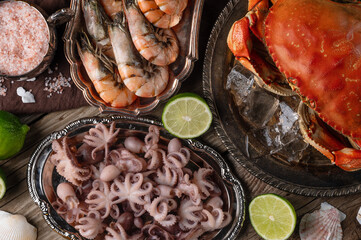 Macro shot of assorted seafood served with lime on rustic wooden background. Cooked crab, shrimps and baby octopuses for dinner. Seafood concept. View from above.