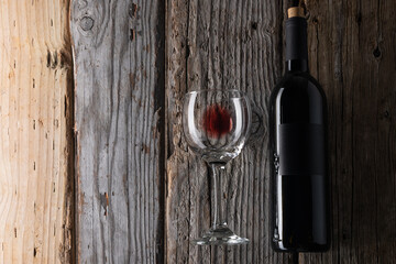Elegant bottle and glass with remains of red wine on wooden background. Advertising and promotion concept. Mock up. Flat lay. View from above.