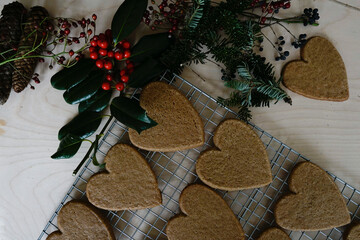 Arrangement of holiday objects and decorations -- green spruce, red berries, ginger heart cookies.