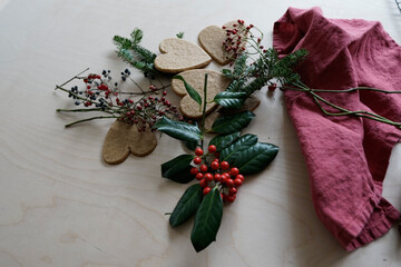 Arrangement of holiday objects and decorations -- green spruce, red berries, ginger heart cookies.