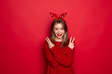 Portrait of pretty woman showing v-sign wear head horns isolated on red background
