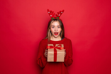 Portrait of pretty woman with gift boxes wear head horns isolated on red background