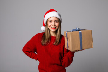 Happy pretty young woman holding gift box isolated over gray background