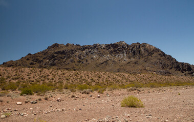Desert landscape. View of the arid sand and rocky mountains under a deep blue sky.	
