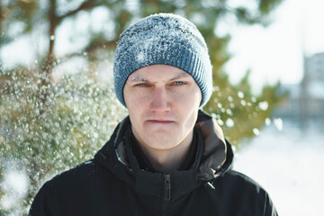 Sullen man surrounded by snowflakes at winter time, close up.